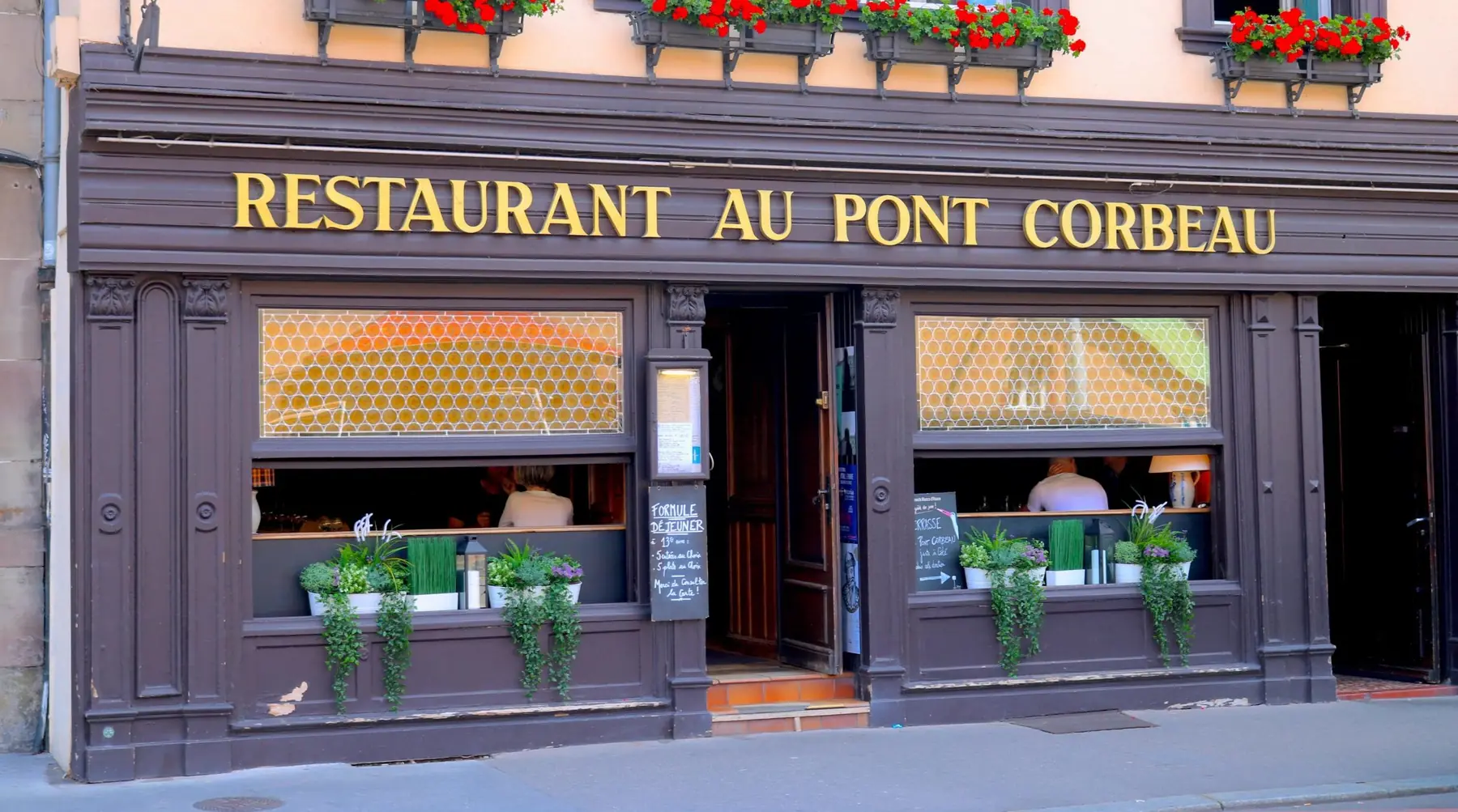 La façade du restaurant Au Pont Corbeau et son enseigne dorée, quai Saint-Nicolas