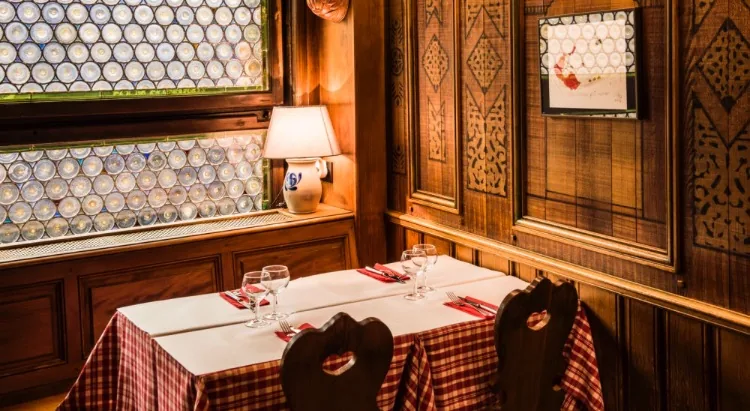 Une table près des vitres en culs de bouteille, boiseries sculptées